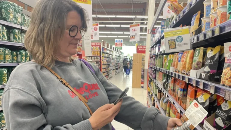 A customer scanning a food product with the Yuka app inside a supermarket.