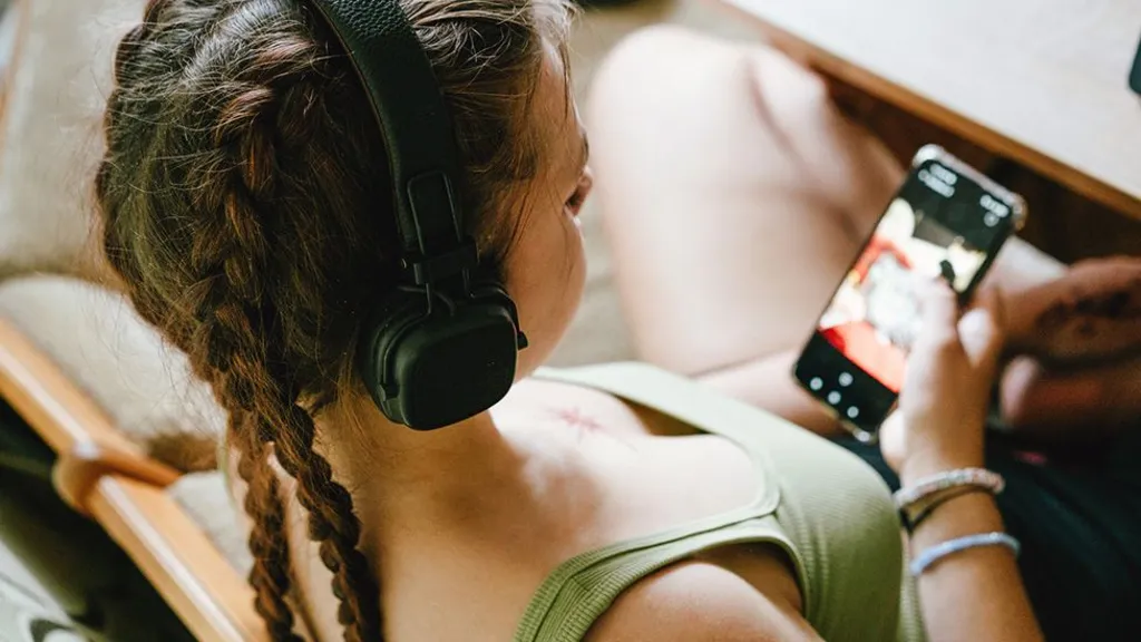 Teenager using YouTube on a smartphone while browsing recommended videos.