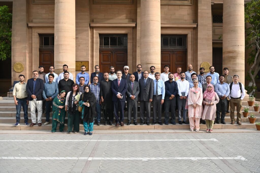Senior State Bank of Pakistan officials pose with journalists after a briefing on the Prime Minister Housing Loan Scheme.