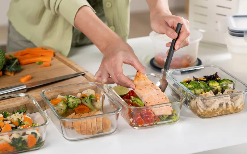 High-protein foods such as eggs, chicken breast, fish, Greek yogurt, beans and pumpkin seeds arranged on a table.