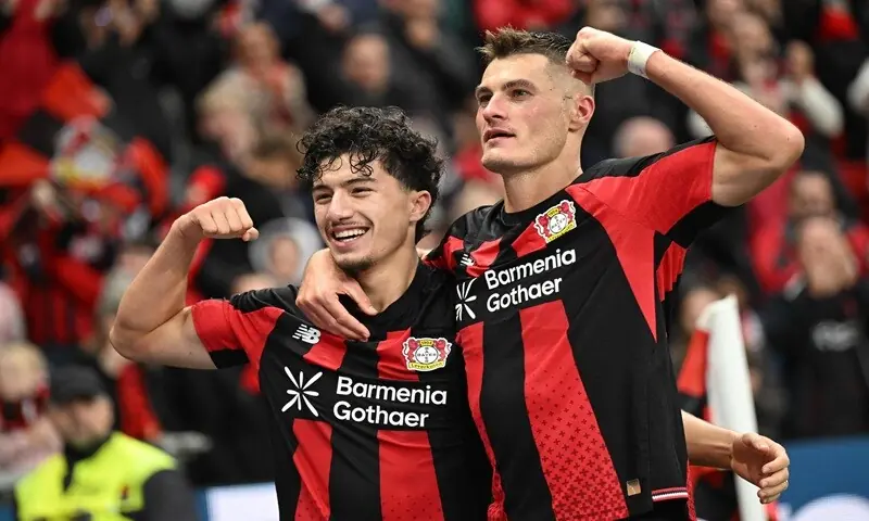 Bayer Leverkusen players celebrate after scoring against Freiburg in a Bundesliga match.